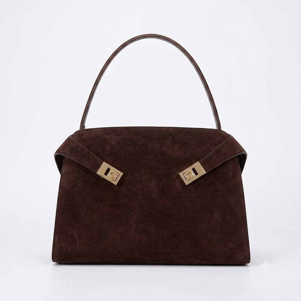 A luxurious dark brown suede handbag with a structured silhouette, featuring elegant gold-tone hardware clasps on the front, available at Bagratica.com.